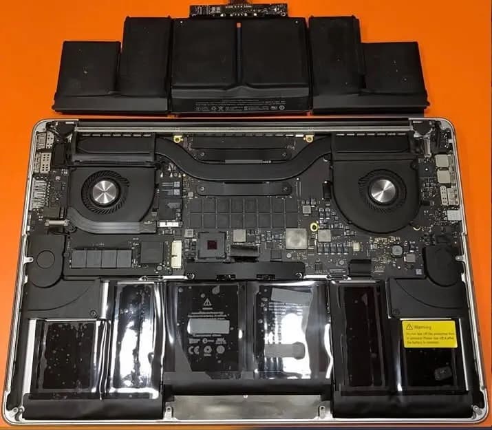 MacBook Pro abierta en el laboratorio de Repárame con la tarjeta madre, ventiladores y baterías a la vista