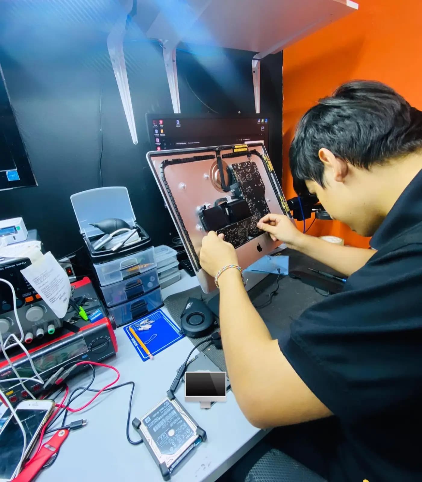 Técnico de Repárame trabajando en una iMac abierta en el laboratorio, con fuente de poder y disco a un lado