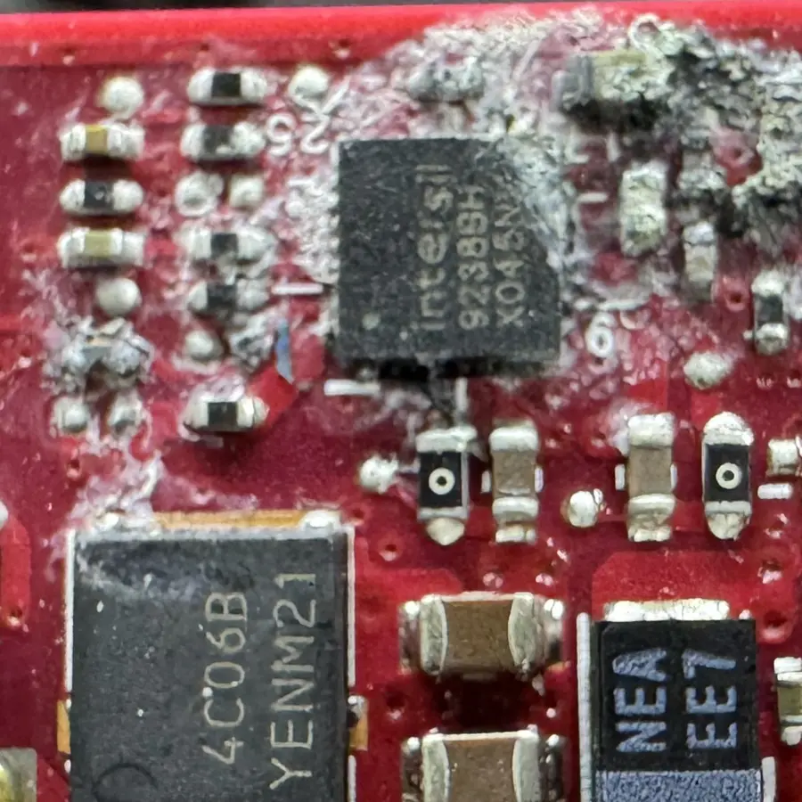 Residuo blanco de líquido seco y componentes corroídos sobre la tarjeta madre de una laptop